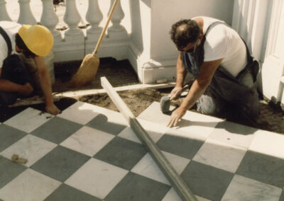 Workers laying marble tiles on the West Portico
